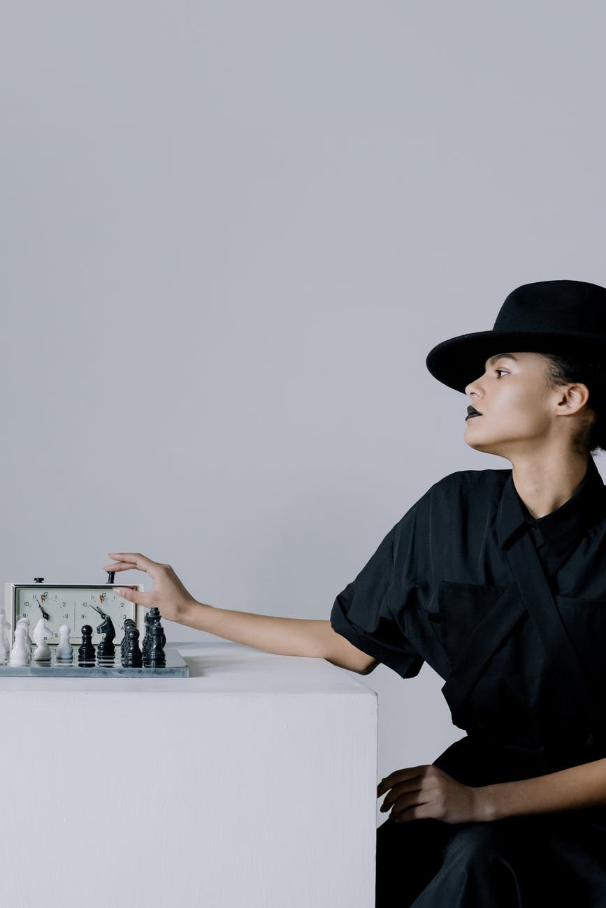 woman in a black hat pressing chess clock