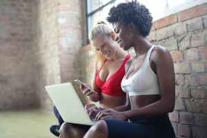two women wearing red and white sports bras sitting near brown wall bricks, sales funnel stages
