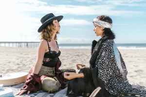 two women sitting on the beach gurus