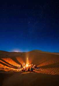 people sitting in front of bonfire in desert during nighttime digital nomad